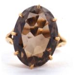 A smokey quartz ring, the oval mixed cut smokey quartz, claw mounted with split shoulders and