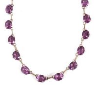 A purple stone riviere necklace, the oval purple stones, each approx. 6 x 8mm diameter, separated by