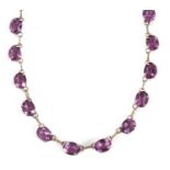 A purple stone riviere necklace, the oval purple stones, each approx. 6 x 8mm diameter, separated by