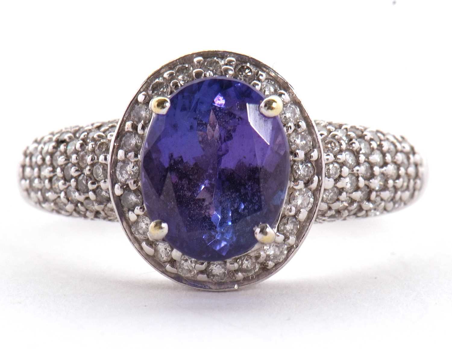 An 18ct white gold tanznite and diamond ring, the oval claw mounted tanzanite, with diamond pave