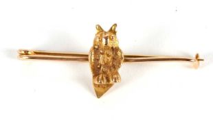 An owl bar brooch, the naturalistically modelled owl sat on a plain bar of unmarked yellow metal, (