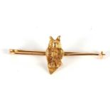 An owl bar brooch, the naturalistically modelled owl sat on a plain bar of unmarked yellow metal, (