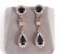 A pair of sapphire and white stone earrings, the round blue sapphire surrounded by small white