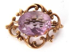 A 9ct amethyst brooch, the oval claw mounted amethyst, surrounded by a scrolled frame yellow gold,