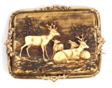 A carved horn brooch, the rectangular horn panel carved with deer and woodland scene, in unmarked