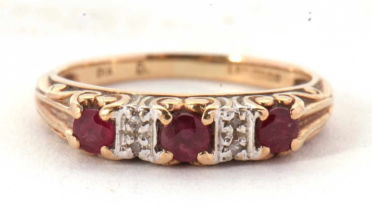 A 9ct ruby and diamond ring, the three round rubies interspaced with two small round diamonds,