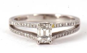 A certified platinum diamond ring, the central emerald cut diamond, 0.64cts, in a crossover four