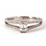 A certified platinum diamond ring, the central emerald cut diamond, 0.64cts, in a crossover four