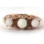 A 9ct opal and garnet ring, the three slightly graudated round opal cabochons, interspaced with