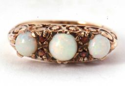 A 9ct opal and garnet ring, the three slightly graudated round opal cabochons, interspaced with