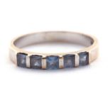 An 18ct synthetic blue spinel ring, set with five square tension set synthetic blue spinels, with