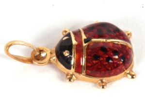A ladybird pendant, the domed red and black enamelled body, with flat back of unmarked yellow
