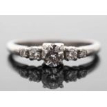 A diamond ring, the central round brilliant cut diamond with a smaller round brilliant and a