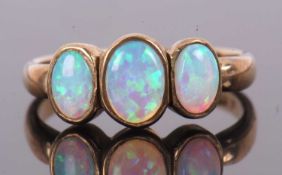 A 9ct opal ring, the three oval opal cabochons in collet mounts, with plain band stamped 375 with