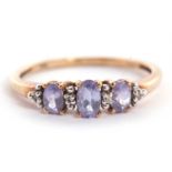 A 9ct tanzanite and white stone ring, the three slightly graduated oval tanzanites interspaced