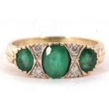 A 9ct emerald and diamond ring, the three graduated oval emeralds, interspaced with two small