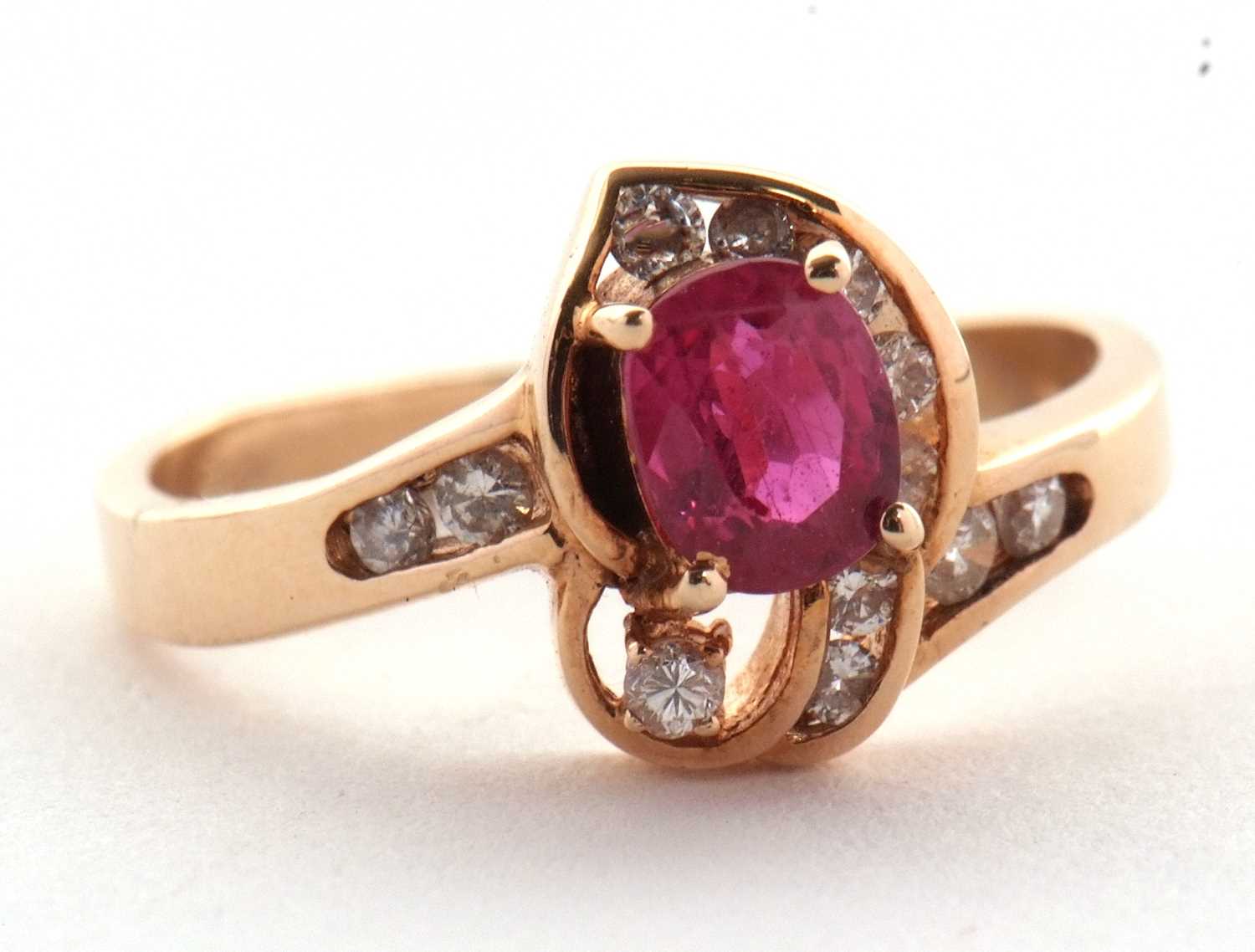 A 14k ruby and diamond ring, the central four claw mounted oval ruby, asymetrically set with small - Image 2 of 4