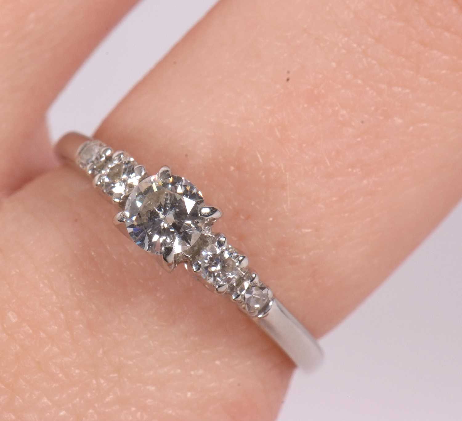 A diamond ring, the central round brilliant cut diamond with a smaller round brilliant and a - Image 9 of 10