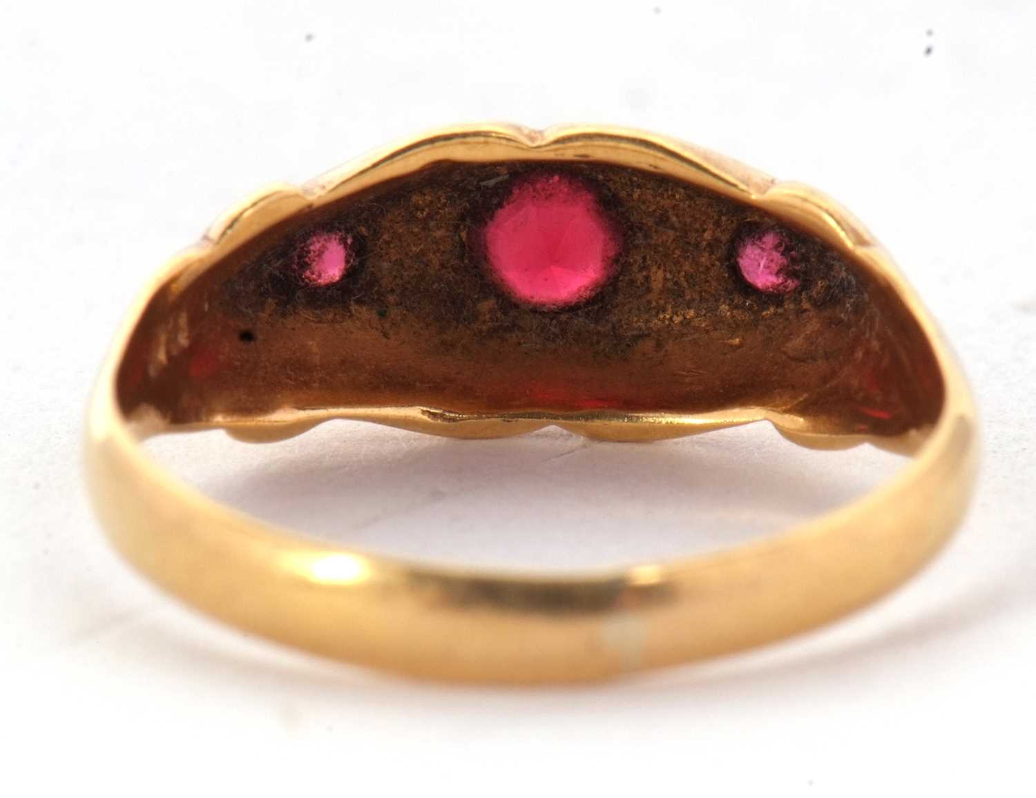 An 18ct red stone and diamond ring, the three round graduated red stones interspaced with diamond - Image 4 of 6