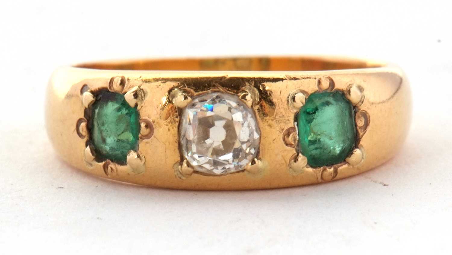 An emerald and diamond ring, the old mine cut diamond, estimated approx. 0.42cts, set to either side