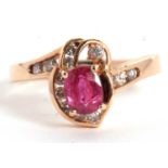 A 14k ruby and diamond ring, the central four claw mounted oval ruby, asymetrically set with small