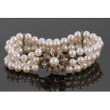 An 18ct cultured pearl, ruby and diamond bracelet, the three rows of round cultured pearls, each