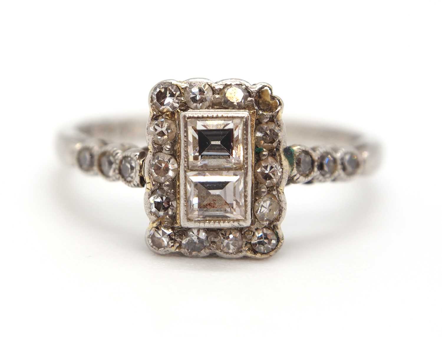 An Art Deco 18ct and platinum diamond ring, set to centre with two square step cut diamonds and