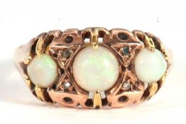 A three stone opal ring, the three graduated round opals interspaced with diamond highlights, all
