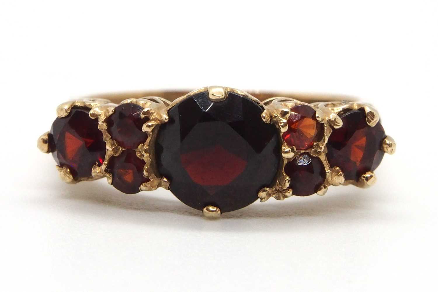 A 9ct garnet ring, the three principal graduated round garnets interspaced with small round garnets,