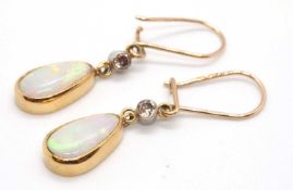 A pair of opal and diamond earrings, the pear shpae opal cabochon drops, collet mounted beneath a
