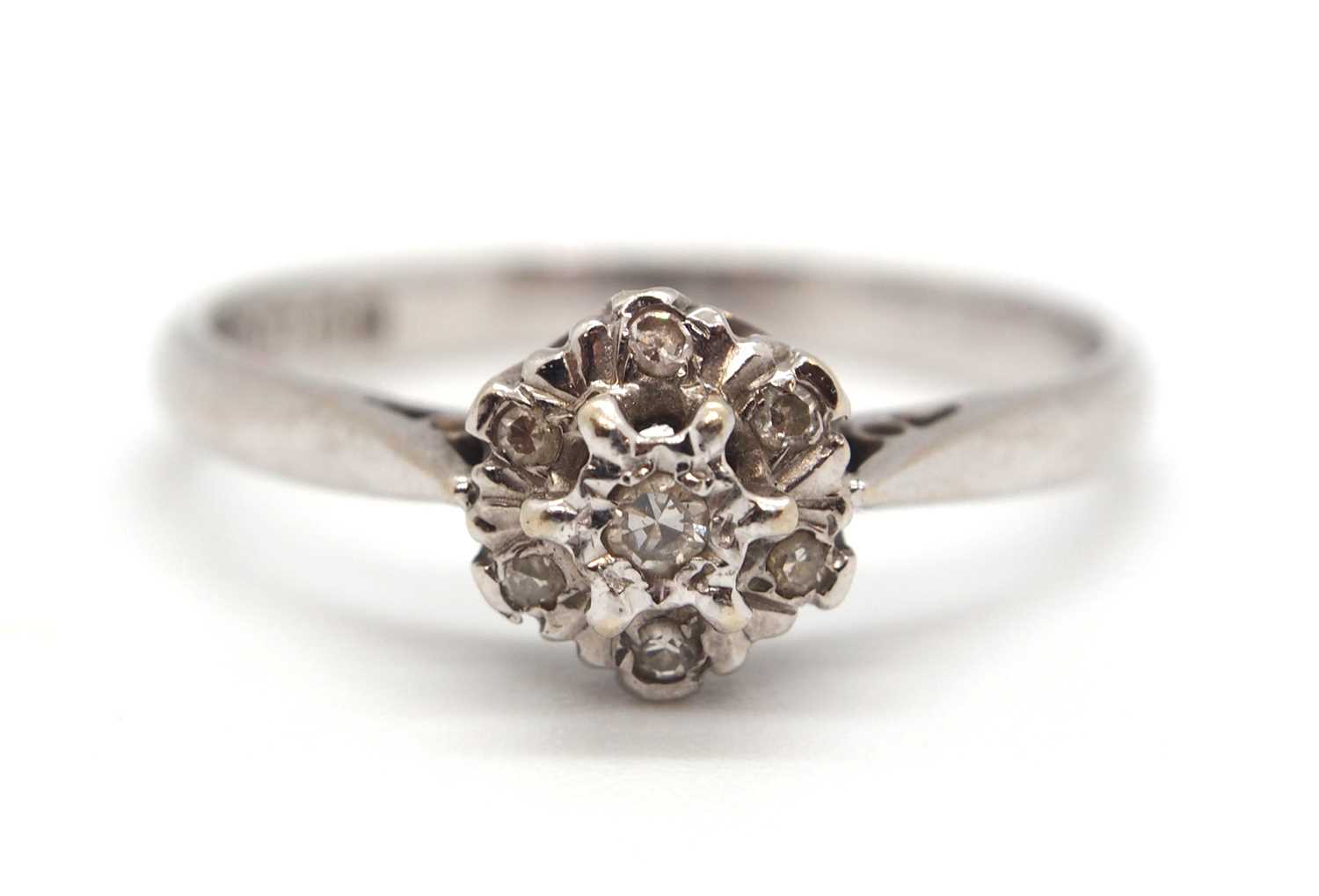 An 18ct white gold cluster ring, comprised of illusion mounted single cut diamonds, with plain