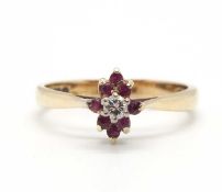 A 9ct ruby and diamond cluster ring, the central round brilliant cut diamond surrounded by small