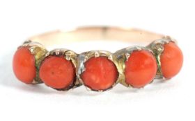 A coral ring, the five round coral cabochons in collar and claw mounts, with shaped shoulders and