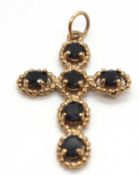 A 9ct sapphire cross, the dark blue sapphires in four claw mounts within beaded framework,