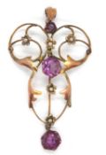 An Edwardian 9ct purple stone and seed pearl pendant, the scrolled frame set with three round purple
