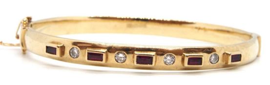 A 9ct ruby and diamond bangle, the hinged bangle with upper half set with alternating round