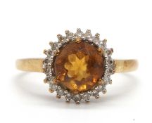 A 9ct citrine and diamond ring, the round mixed cut citrine surrounded by round brilliant cut