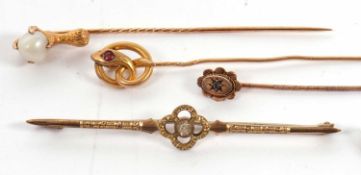 Three stick pins and a brooch: to include a 14ct 'pearl' and eagle claw stick pin, stamped 585; an