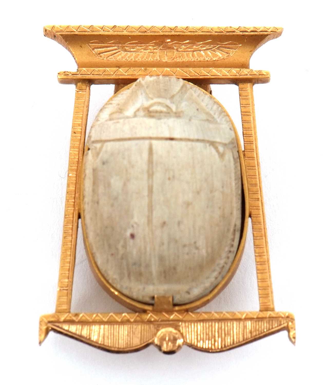 A scarab brooch, the carved stone scarab in a collet mount within a stylised Egyptian style frame,
