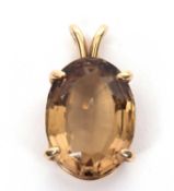 A 14K quartz pendant, the oval lemony-brown quartz in a four claw mount with split bale and