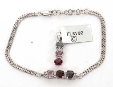 A 9ct three stone pendant and a similar three stone bracelet: the necklace set with raspberry,