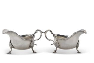 Pair of George VI silver sauce boats of typical form having wavy gadroon rims, leaf capped scroll