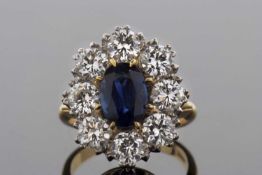 A sapphire and diamond cluster ring, the central claw oval sapphire, approx. 8.8 x 5.8 x 4.3mm,