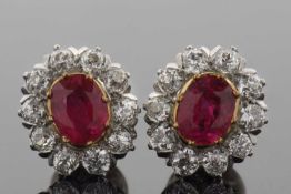 A pair of ruby and diamond cluster earstuds, the oval rubies in rubover mounts and surrounded by