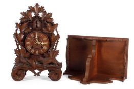 A Black Forest cuckoo clock of typical form, dial surrounded by carved leaf and animal decoration,