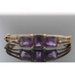 A late 19th century amethyst and seed pearl bangle, set with three rectangular amethysts in collet