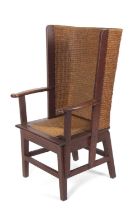 An early 20th Century oak framed Orkney chair of typical form with arched back, drop in seat and