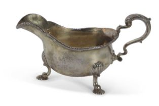 George II silver sauce boat of typical form with leaf capped scroll handle, raised upon three