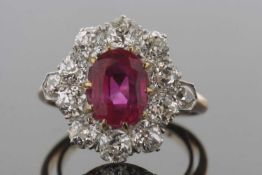 A ruby and diamond cluster ring, the oval claw mounted ruby, approx. 8.8 x 6.8 x 4.0mm, surrounded