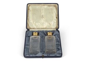 A cased pair of silver, gilt and glass scent/cologne bottles, the rectangular shaped bottles with